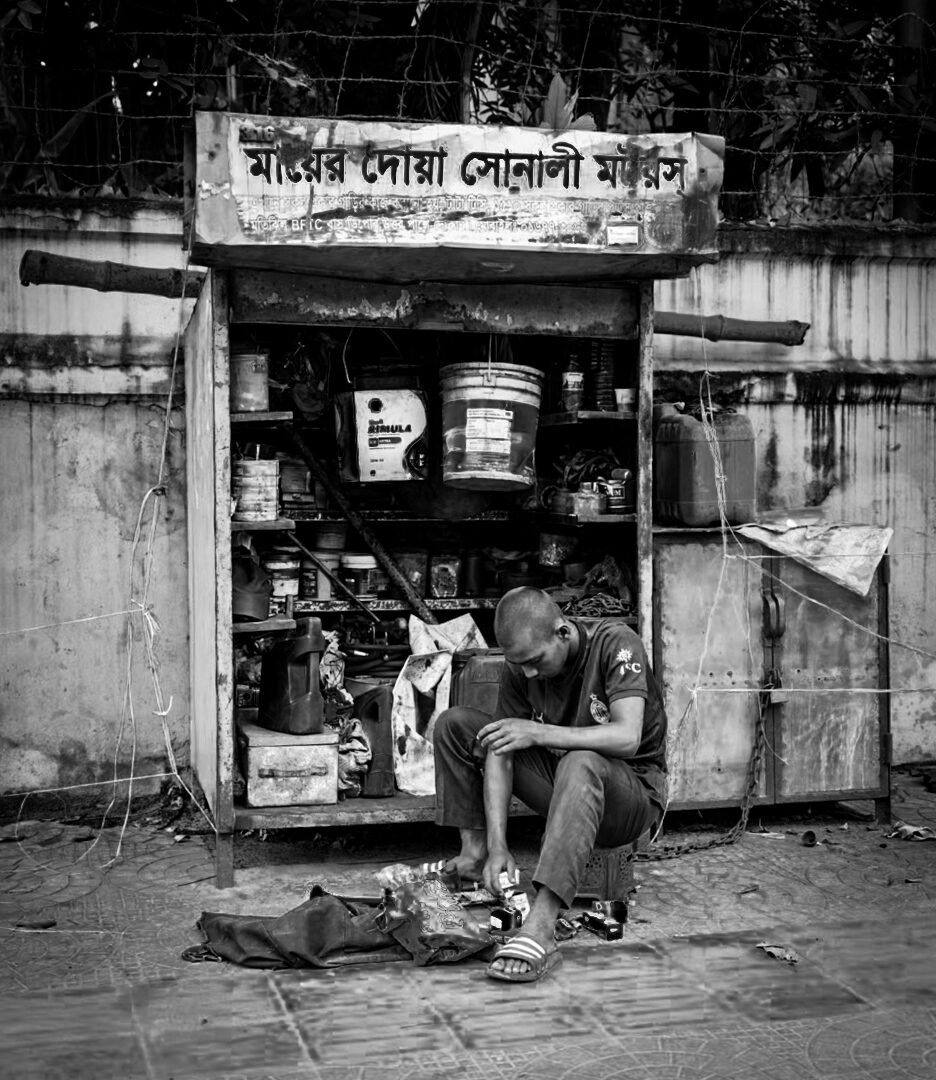 Man repairing shoes at a roadside stall