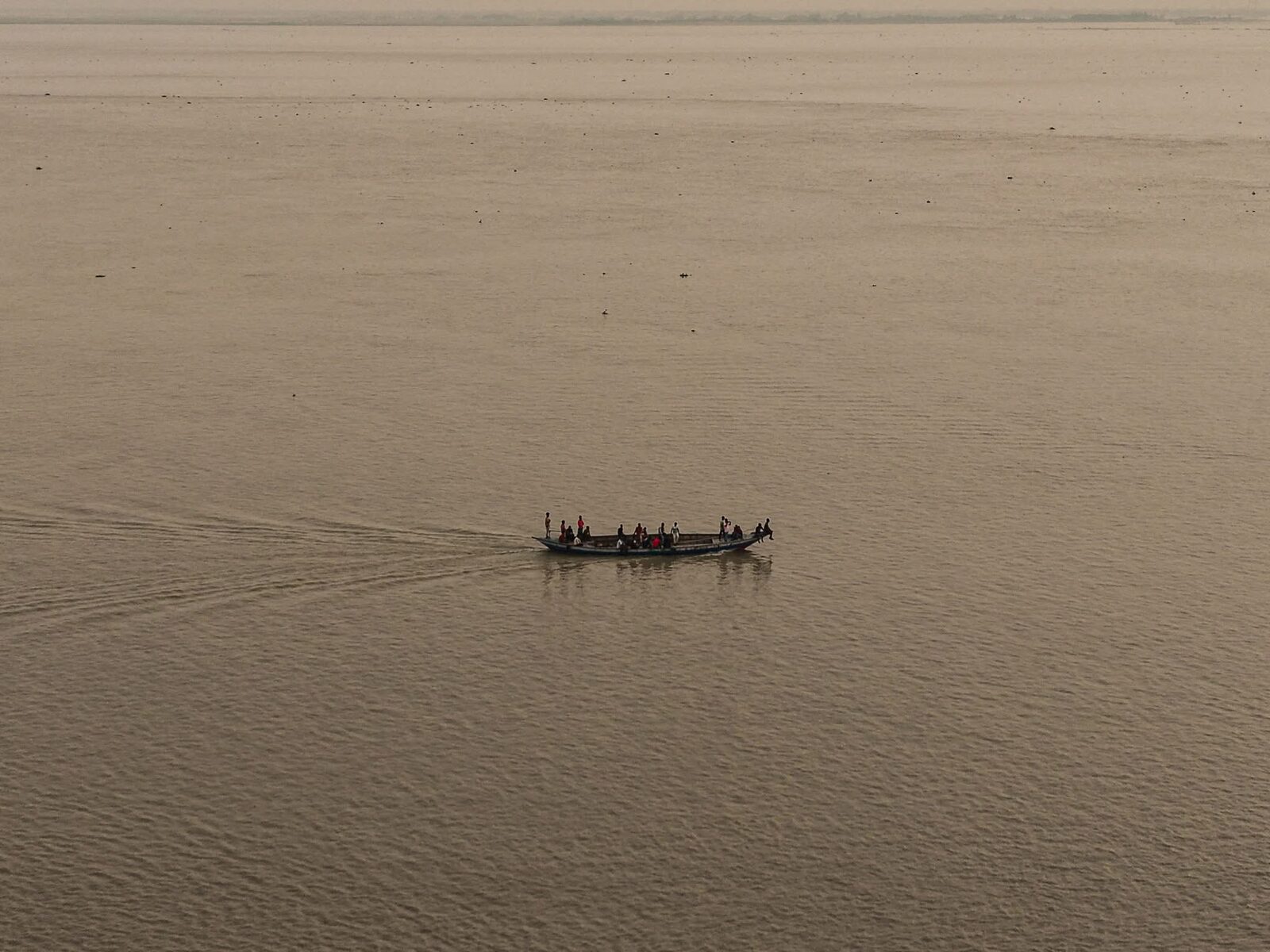 Aerial view of a small boat crossing a wide river